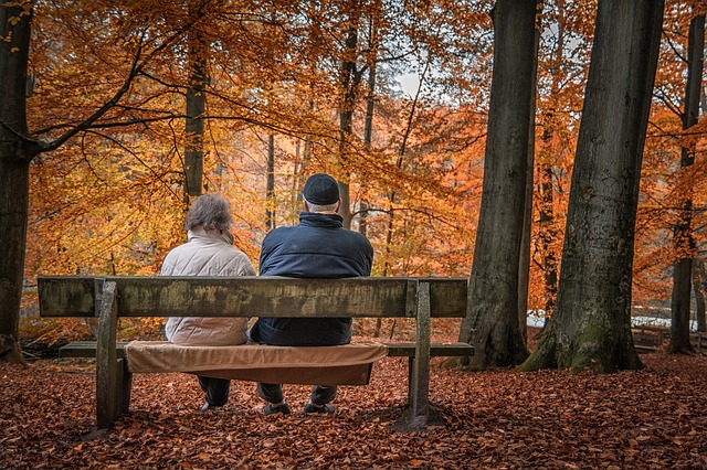 Dvojice sedící na lavičce v podzimním lese